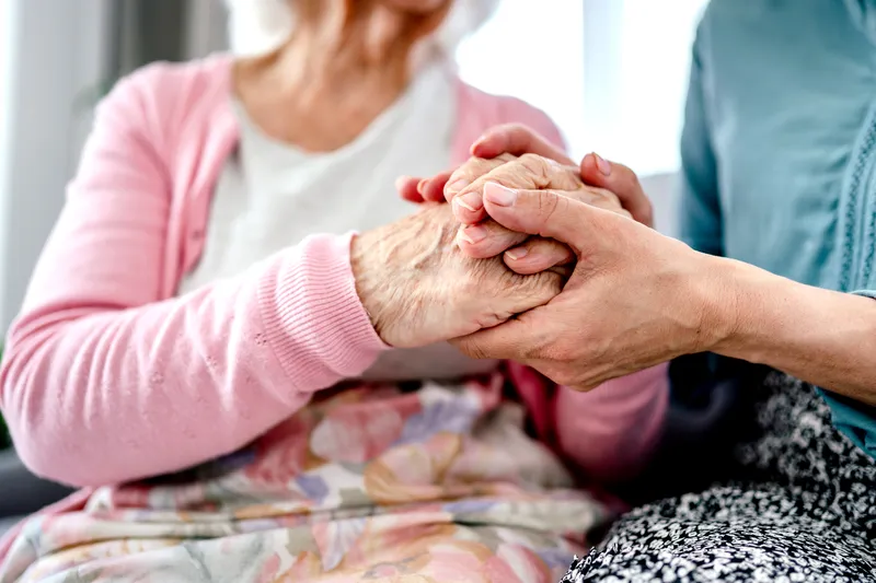 Wir nehmen uns Zeit für Sie. Nahaufnahme von verschränkten Händen während eines Beratungsgesprächs der Caritas Sozialstation.